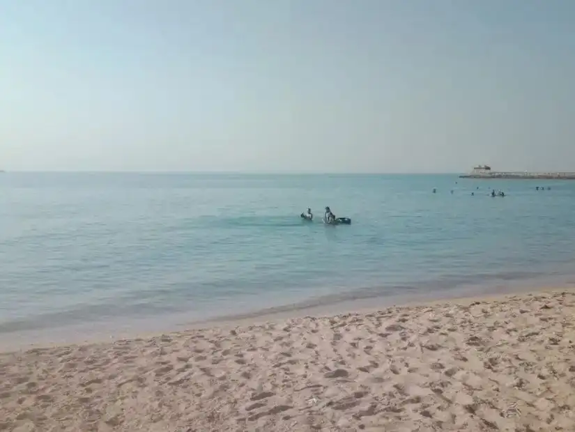 The calm waters of Ain Sokhna beach with a few boats in the distance and a serene atmosphere.