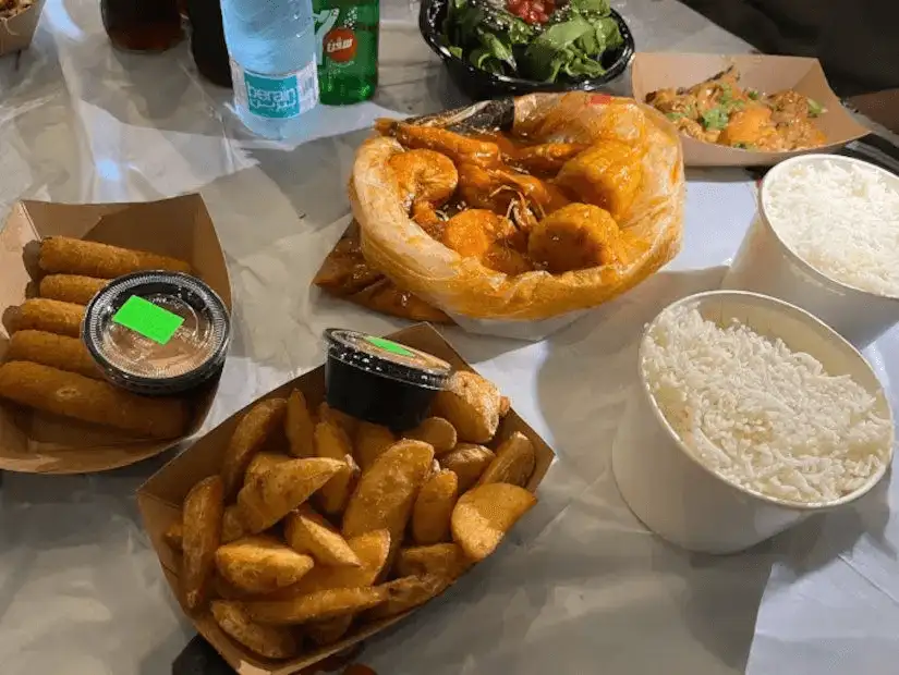 A casual meal featuring fried plantains, spring rolls, prawn stew, and fluffy white rice.