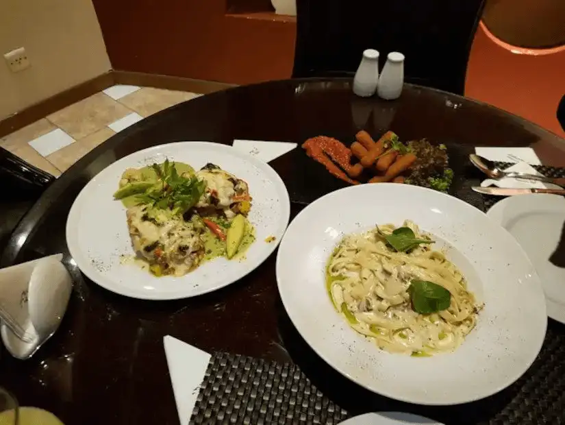 A modern restaurant setting with chicken parmesan, spaghetti alfredo, and an assortment of side dishes.