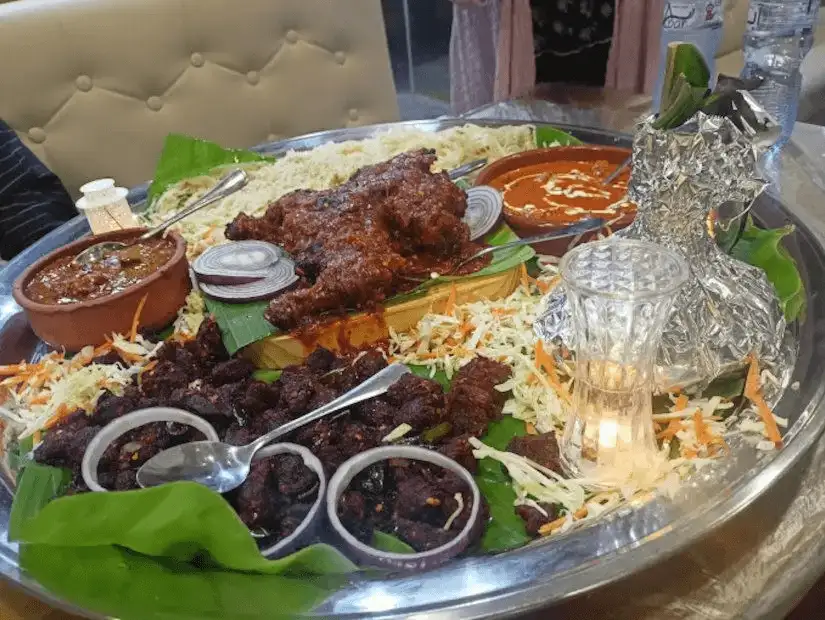 A grand spread of Arabic mixed grill, featuring kebabs, roasted lamb, and accompanying sauces on a bed of rice.