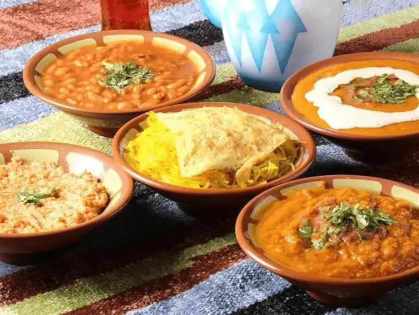 A traditional Saudi breakfast featuring fava beans, scrambled eggs, and grilled vegetables.