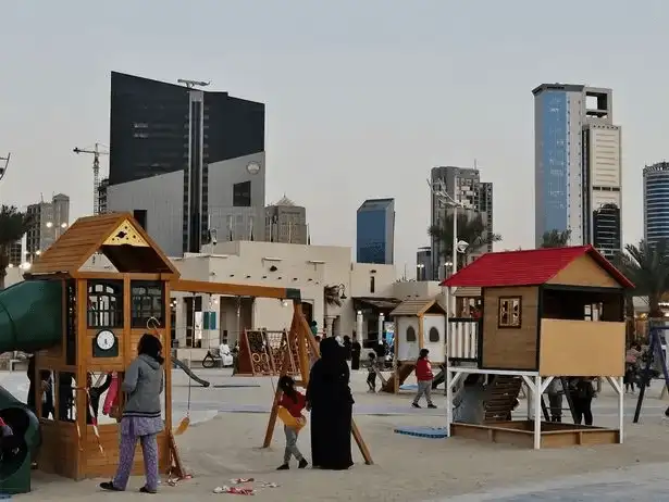 Families enjoying a sunny day at Al Bahhar Heritage Village with a view of Kuwait City’s skyline.
