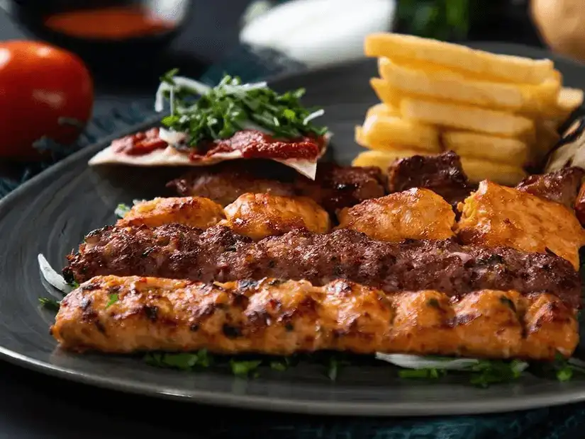 Grilled chicken and beef kebabs with fries and salad, a flavorful feast.