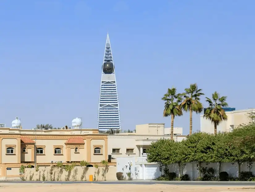 Al Faisaliyah Center viewed from a distance with traditional Riyadh architecture in the foreground.