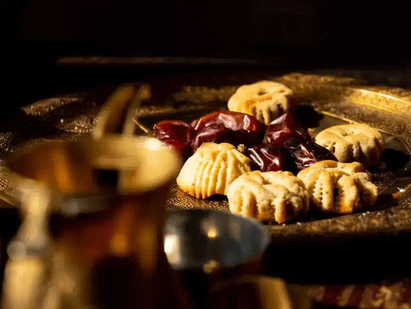 A tray of traditional Arabic sweets and dates served with coffee.