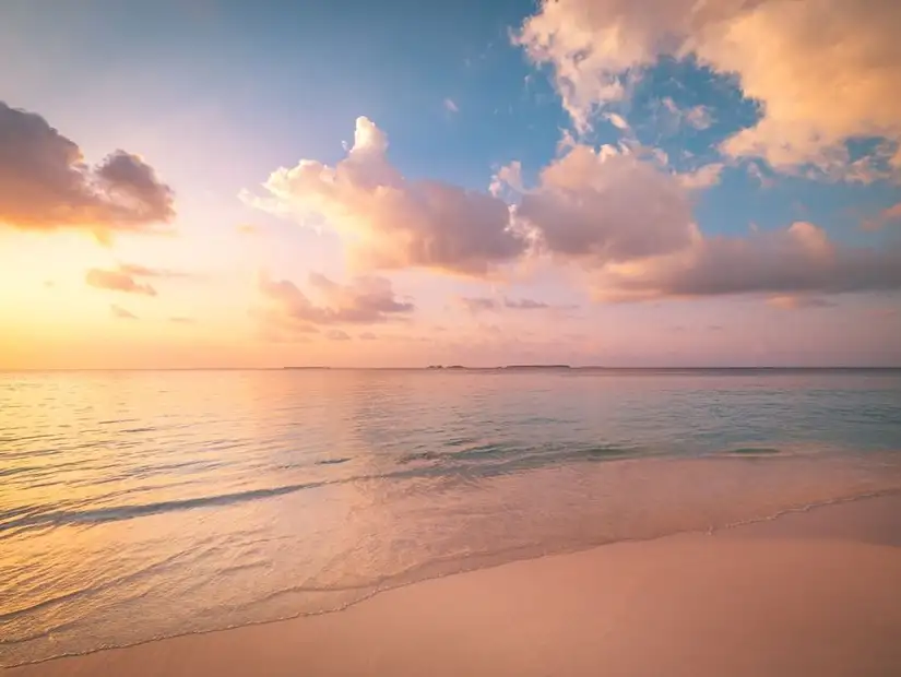 Golden sunset casting a warm glow over the serene beach.