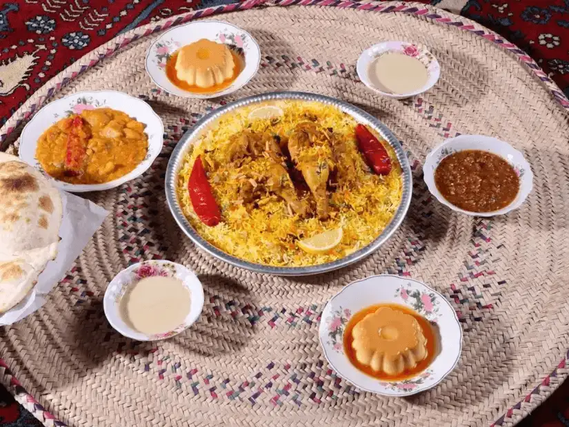 A flavorful Gulf-style rice dish with chicken and rich accompaniments like sauces and desserts.