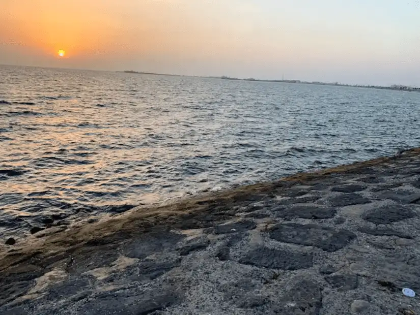 Calm ocean waters meeting a sturdy stone walkway at sunset.