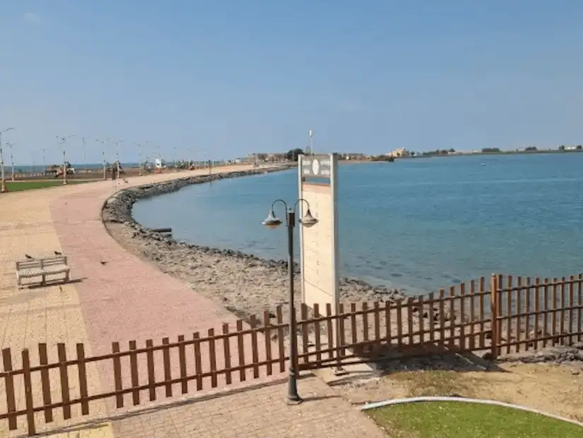 Panoramic view of a curving coastline with clear waters, inviting for beachgoers.