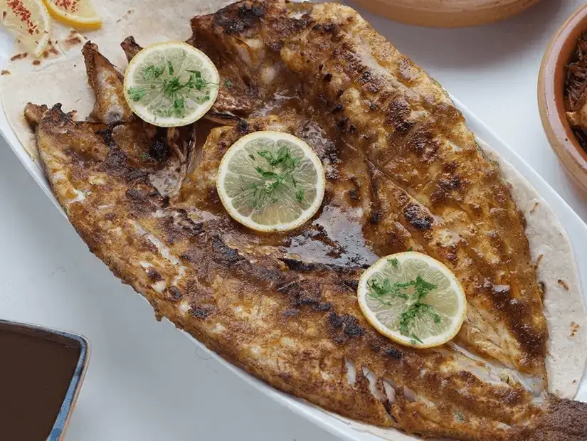 Whole grilled fish garnished with lemon and herbs, a seaside delight.