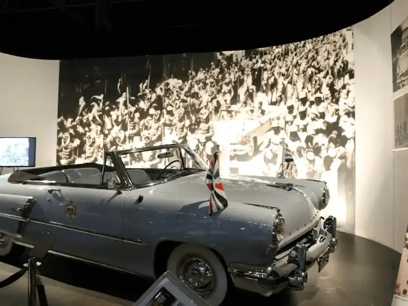 Vintage car in a museum setting, symbolizing a celebrated past amidst historical imagery.