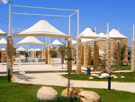 Sunny day at a modern park with protective canopies and lush greenery.