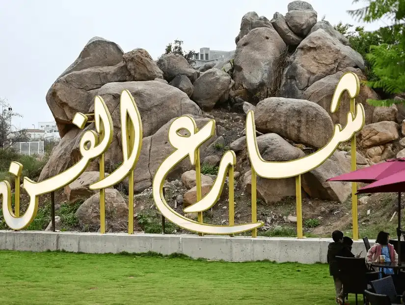 Welcome sign at Art Street, surrounded by greenery and rocks.