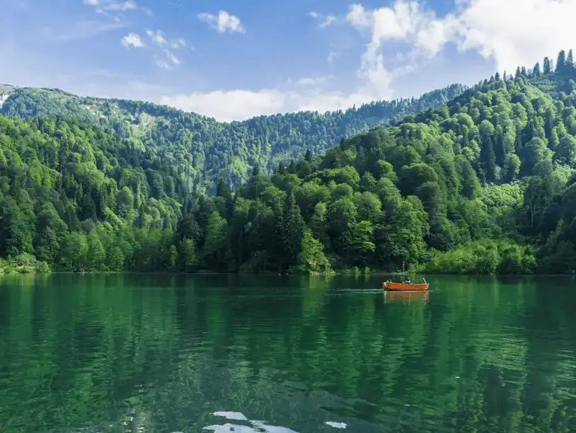 A small boat on the serene waters of Karagöl surrounded by lush green mountains in Artvin.