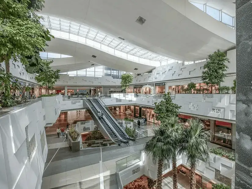 Spacious indoor promenade lined with shops and eateries under a unique, sculptural ceiling.