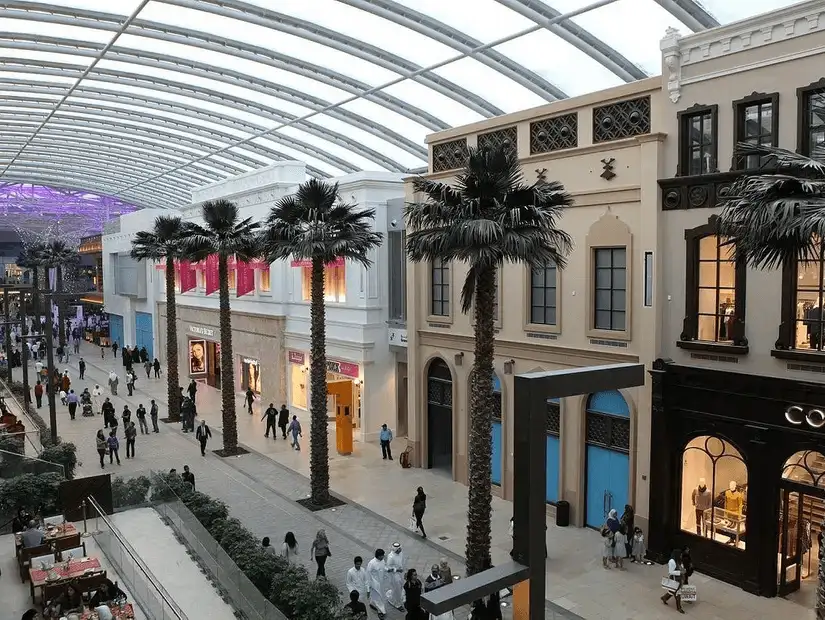 Modern luxury shopping corridor with high-end boutiques under a geometric glass roof.