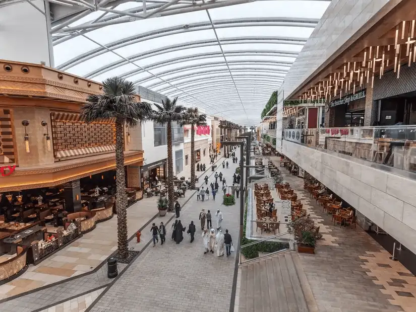 Bustling shopping avenue under a curved translucent roof with diverse dining options.