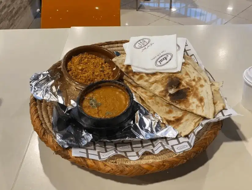 Traditional meal with dal, curry, and flatbread in a rustic presentation.