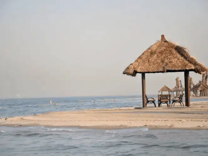 A quaint beach hut offering shade and a scenic view of the sea.