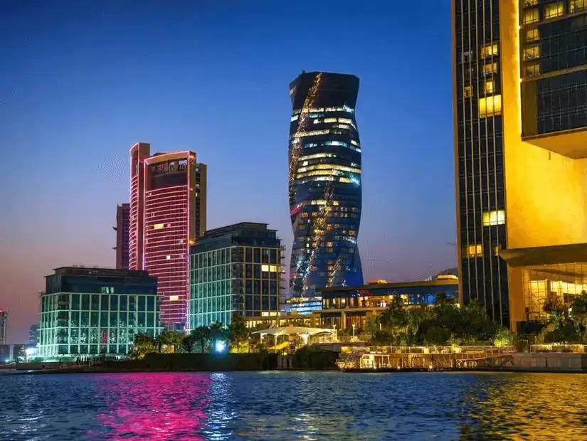 Bahrain’s striking skyscrapers illuminated at night, reflecting over the gulf waters.