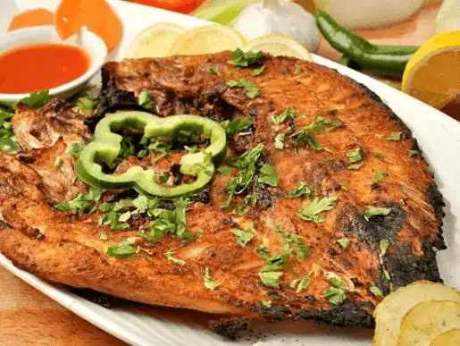 Grilled fish garnished with green peppers and herbs, a delightful seafood option.