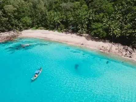 A peaceful boat floating in the turquoise waters of Banana Beach, surrounded by lush greenery.