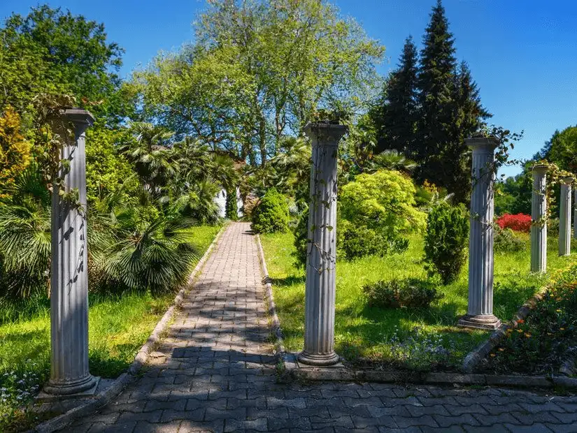 Pathway with columns and lush greenery in a park.