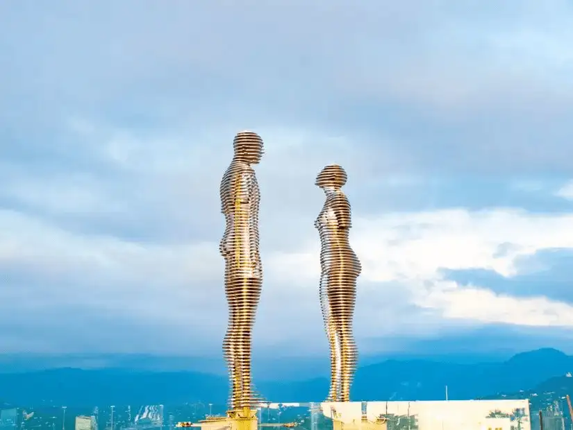 Metal sculptures of a man and a woman facing each other.