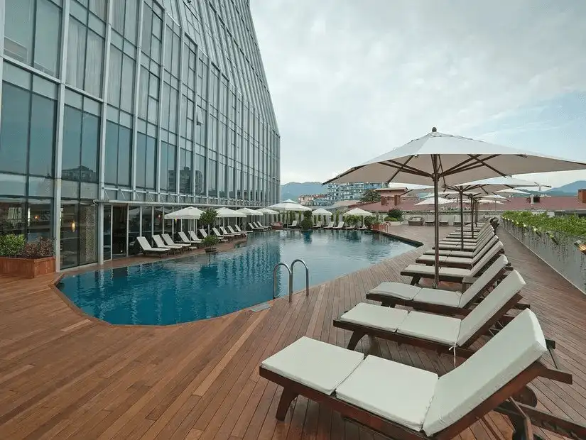 Rooftop swimming pool with lounge chairs and umbrellas.