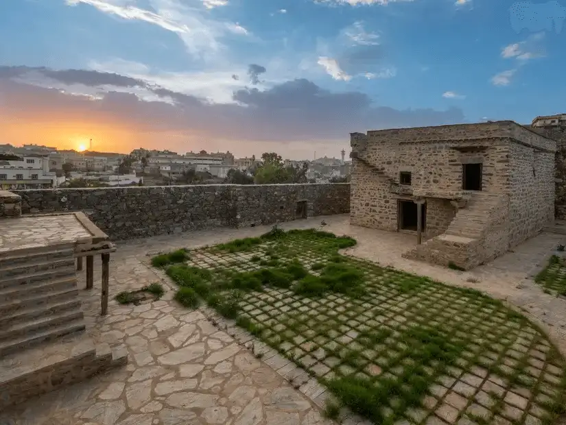 Bin Raqoush Village at sunset, showcasing stone architecture.