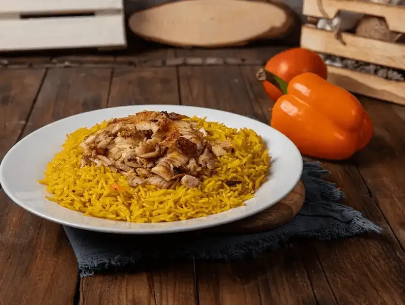 Spiced rice with roasted chicken, a traditional dish garnished with fried onions and fresh vegetables.  