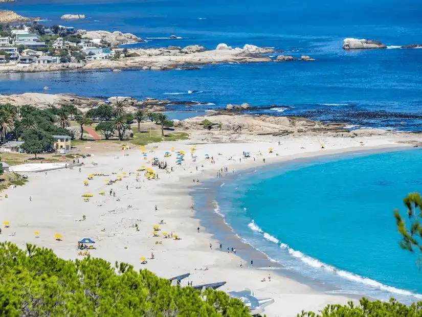 A vibrant view of Camps Bay beach with turquoise waters and yellow umbrellas.