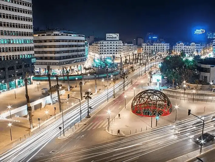 Night view of a busy intersection in Casablanca with light trails and illuminated buildings.