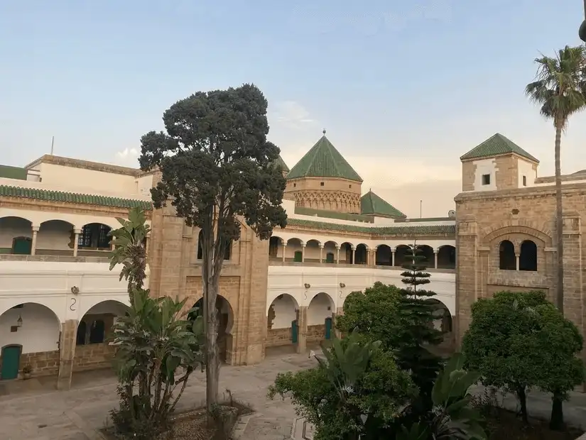 White-walled building with green roofs and a tall minaret in Casablanca.