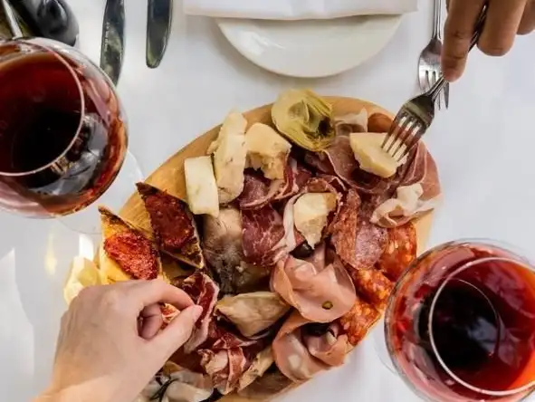 A well-curated selection of cheeses and cured meats, paired with a glass of red wine.
