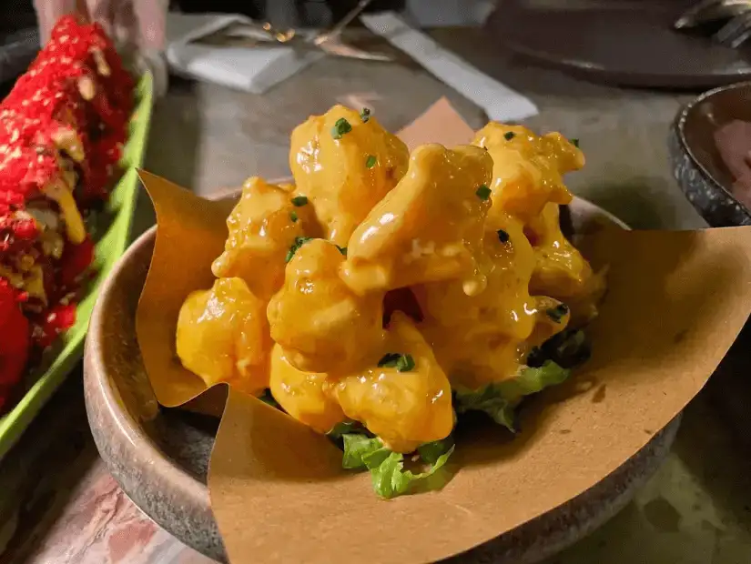 A gourmet dish of tender shrimp tossed in a creamy sauce, served in a small bowl with a garnish of fresh herbs.