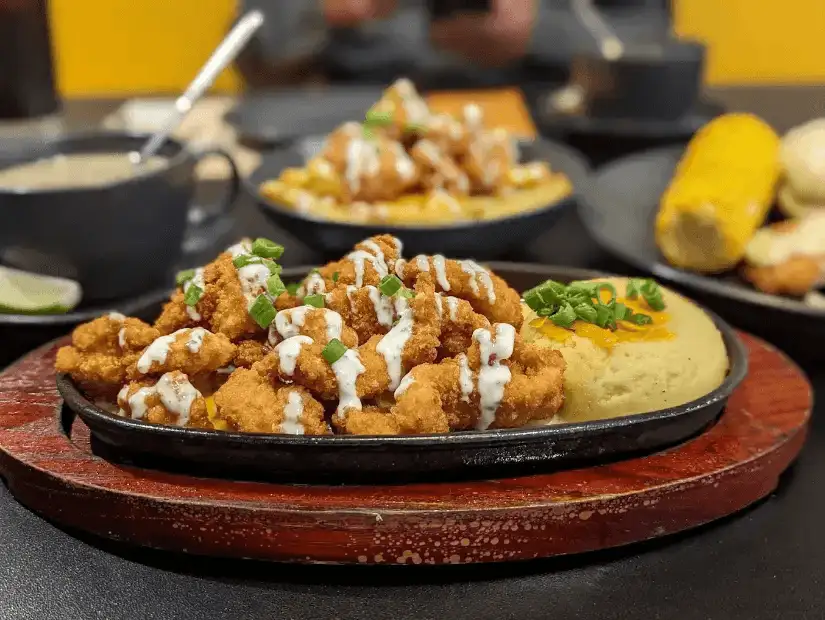 Fried chicken, mashed potatoes, and sauce served on a sizzling platter.