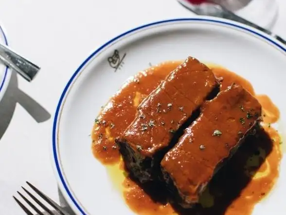 Tender short ribs glazed with a rich, savory sauce, served on a classic porcelain plate.