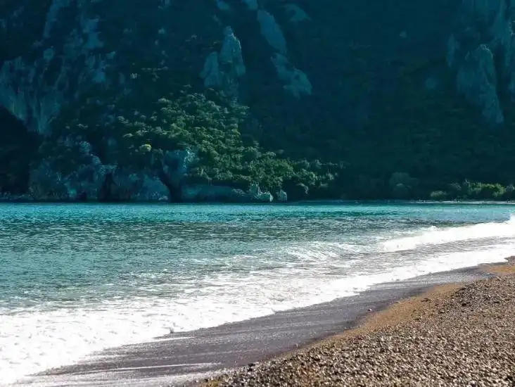  A serene view of Cirali Beach with a calm sea and beautiful mountainous backdrop.