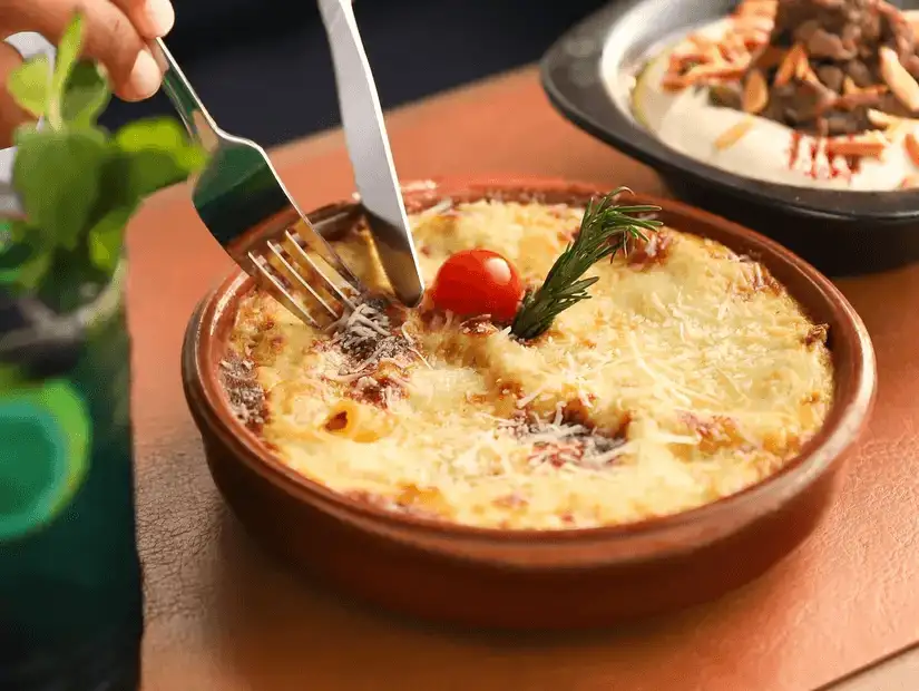 Rich and cheesy baked pasta dish, topped with a fresh cherry tomato.