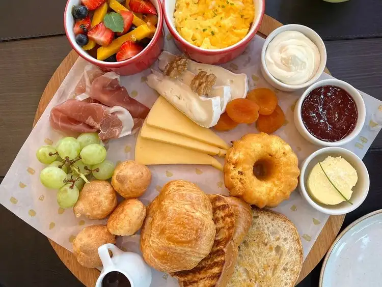 A delicious brunch platter featuring a variety of fruits, cheeses, and pastries.