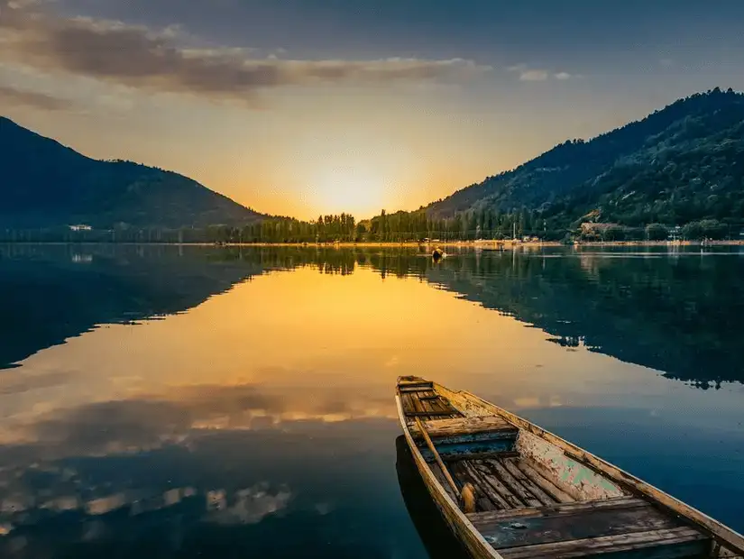 A peaceful boat floating on the tranquil waters of Dal Lake, reflecting the surrounding mountains.