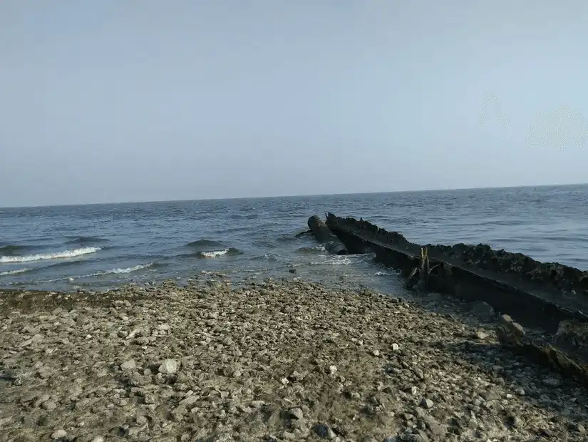 A rugged beach with scattered rocks along the shoreline, touched by gentle ocean waves.