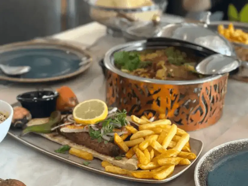 Grilled kebabs served with crispy fries, fresh vegetables, and a lemon wedge.