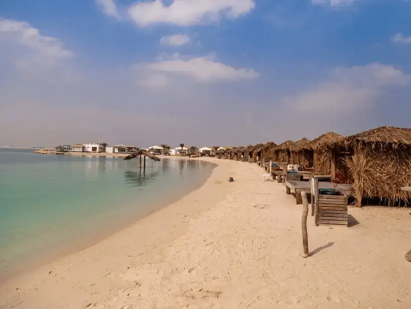 Peaceful sandy shores and beach huts on Dar Island, offering a serene escape by the sea.