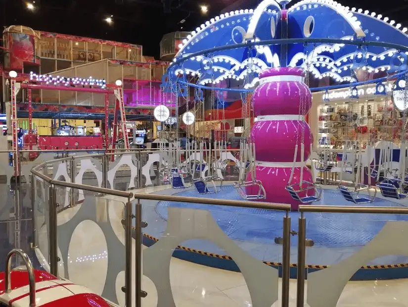 A colorful indoor amusement area with bright lights and a carousel for children at Dragon Mart.