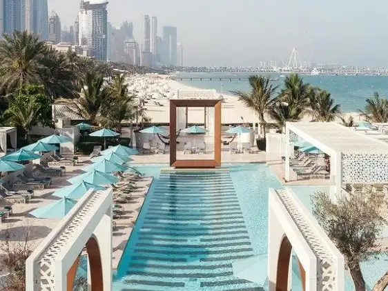 Elegant pool and beach setup at Drift Beach with a view of Dubai's skyline.