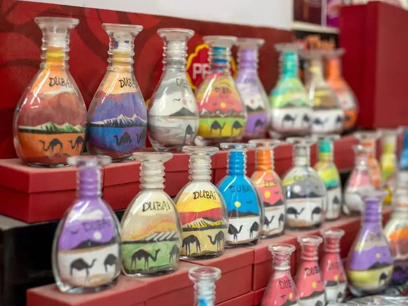 Vibrant sand art bottles showcasing desert landscapes at a gift shop.