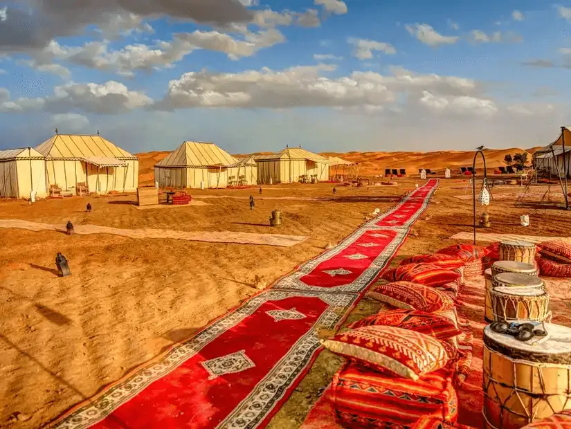 Luxurious desert camp setup in Erg Chebbi with colorful carpets and tents.