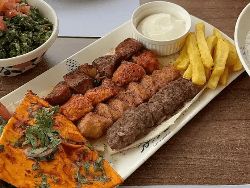A spread from Fatteh w Sanobar, showcasing a traditional Middle Eastern meal with rich dishes and vibrant sides.